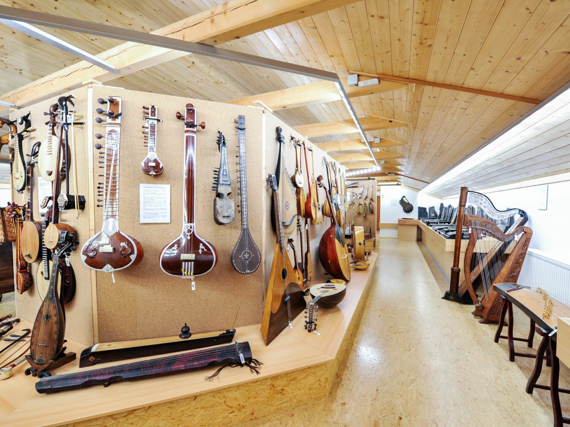 A room with wooden ceilings and walls, displaying various string instruments.