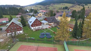 A residential area with houses, a tennis court, and a playground with trampolines.