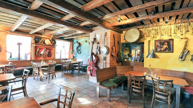 A restaurant with wooden tables and chairs, a tiled floor, and various musical instruments on the walls.