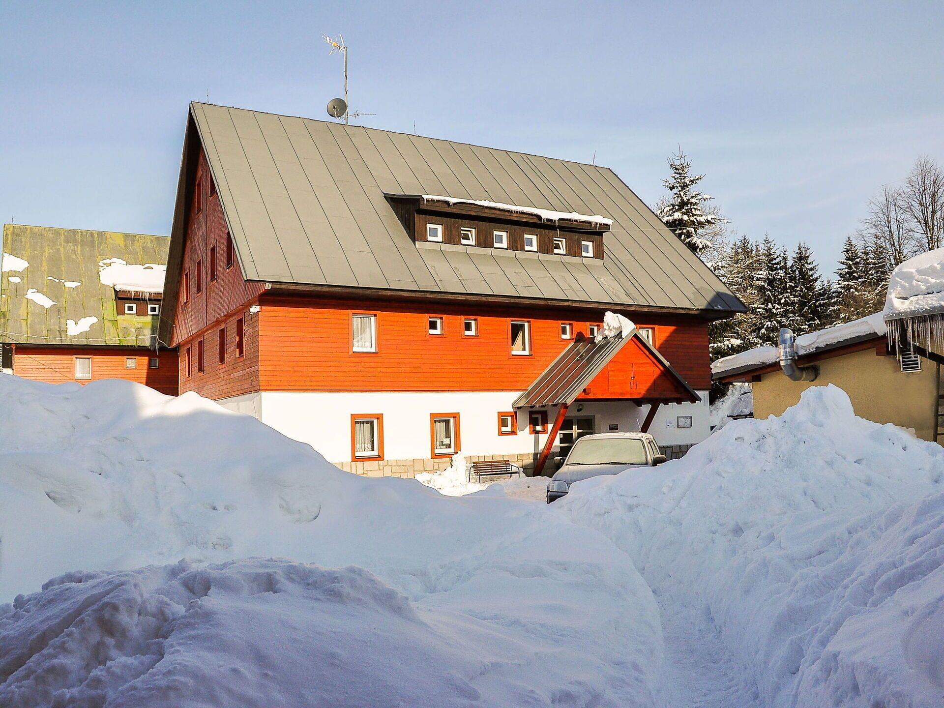Um edifício vermelho e branco com telhado inclinado, rodeado de neve.