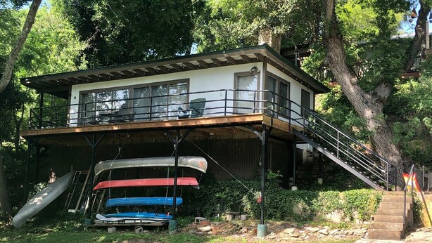 A two-story house with a balcony, a wooden deck, and a staircase leading to the upper level.