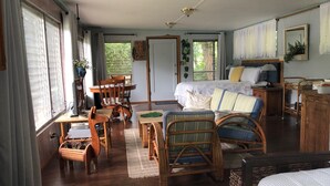 A cozy room with a bed, a desk, a chair, and a dining table.