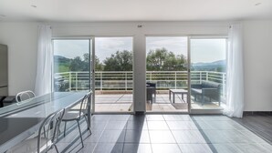 Ein geräumiges Zimmer mit einer großen Schiebetür, die auf eine Terrasse mit Tisch und Stühlen führt.