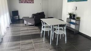 Ein modernes Wohnzimmer mit einer Couch, einem Esstisch mit Stühlen, einem Fernseher und einem Bild an der Wand.