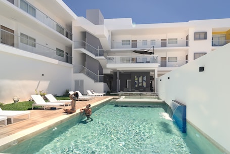 Una piscina al aire libre, sombrillas, sillones reclinables de piscina