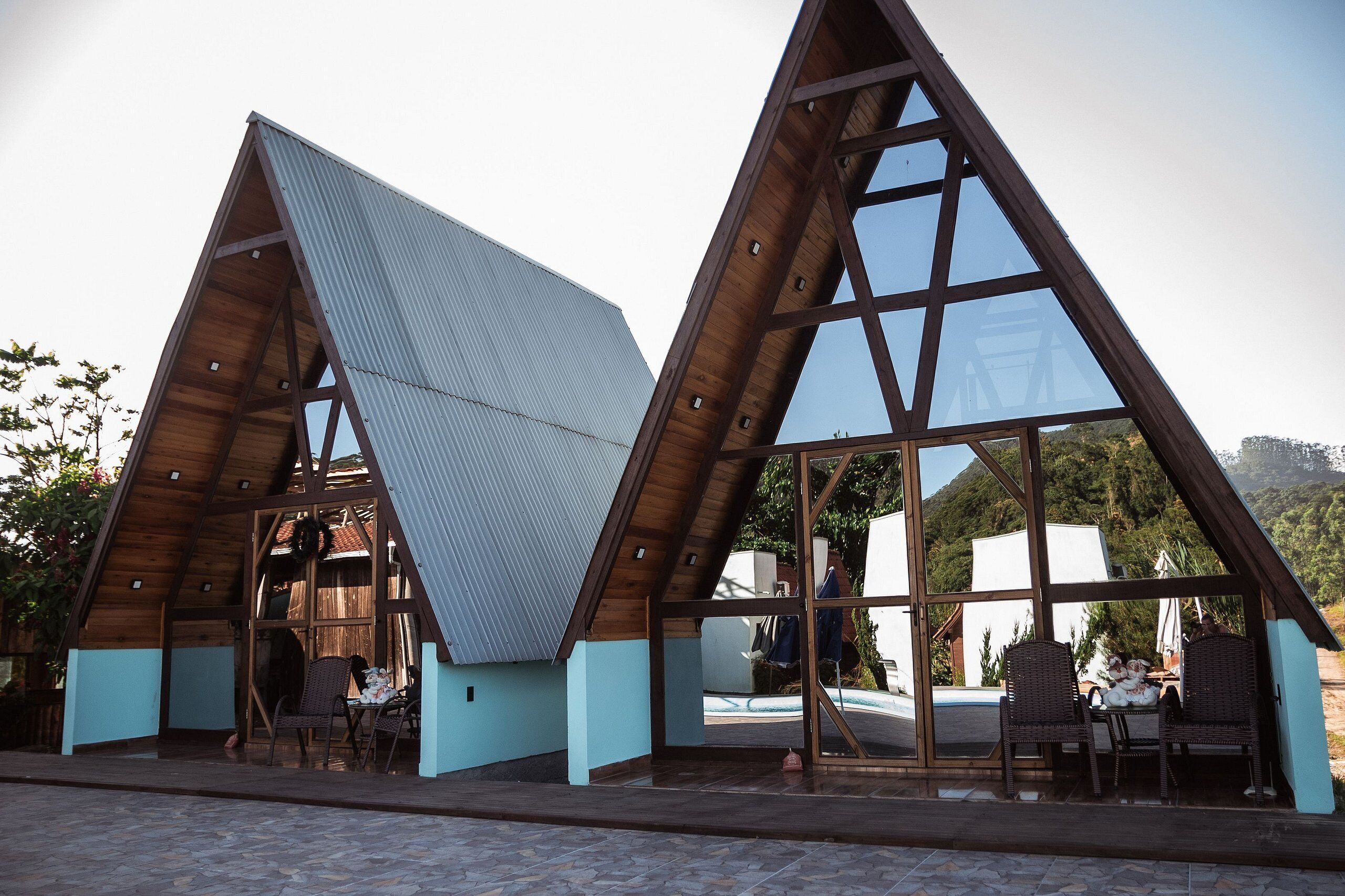 A triangular building with large windows and a patio area with chairs.