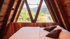 Ein Schlafzimmer mit großem Fenster, Holzwänden und einem Bett mit Kissen.