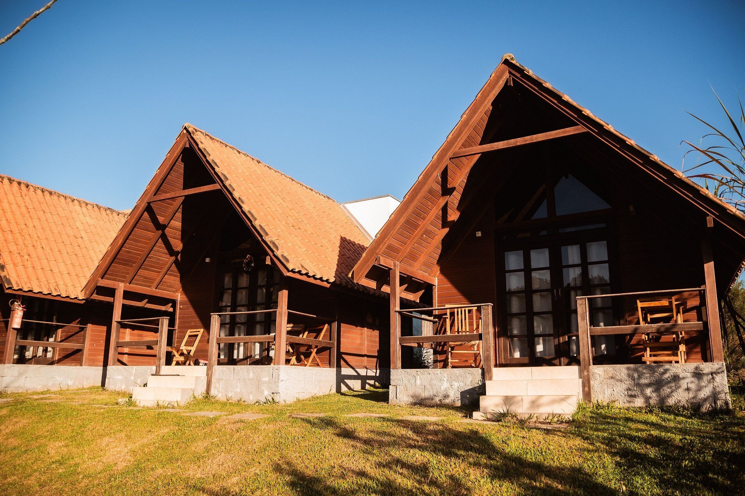 A wooden cabin with a sloped roof, large windows, and a porch area.