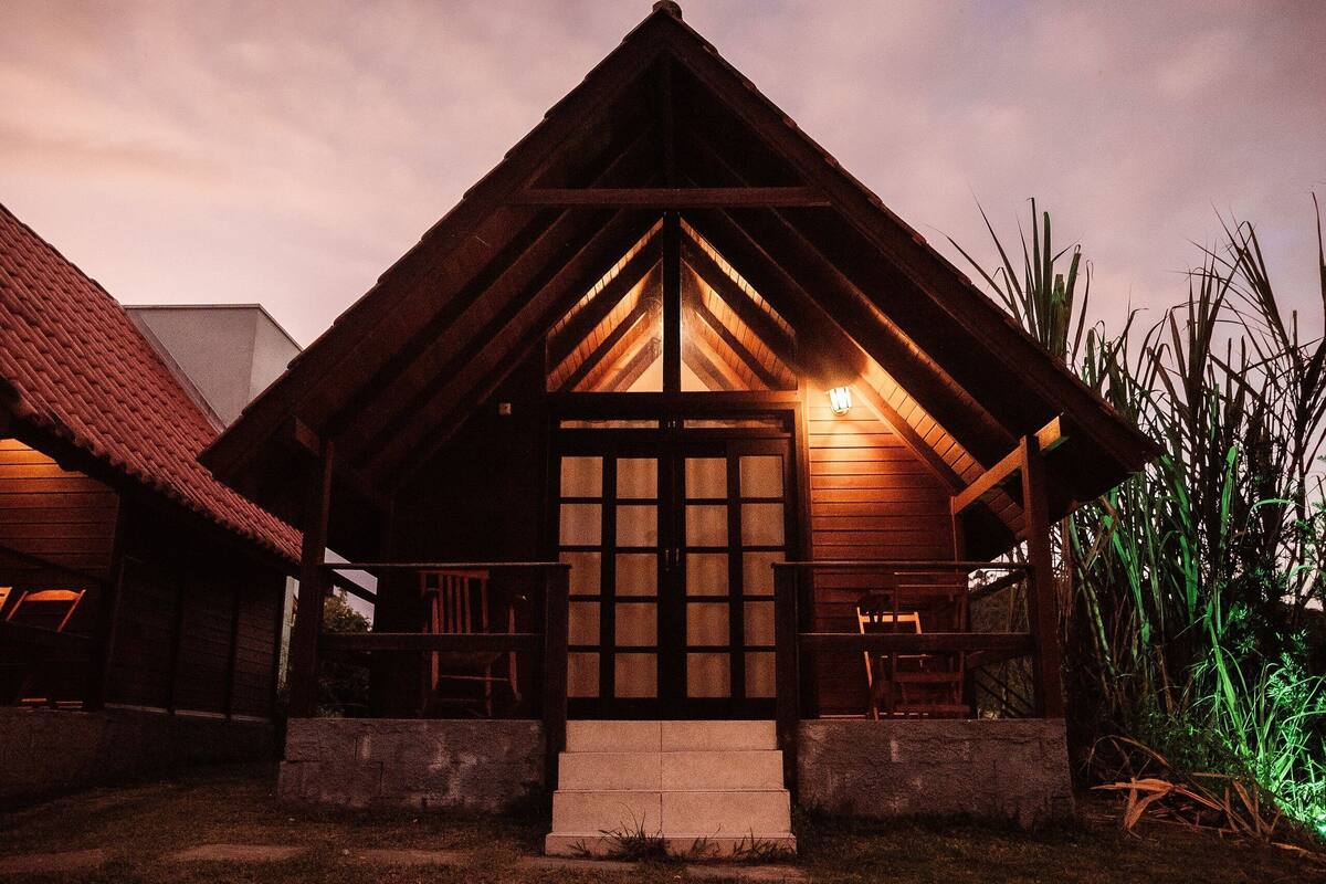A wooden cabin with a prominent gabled roof and a central door with glass panels.