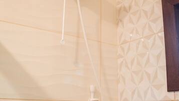 A shower with a handheld attachment, a wall-mounted control panel, and a geometric tile pattern on the wall.