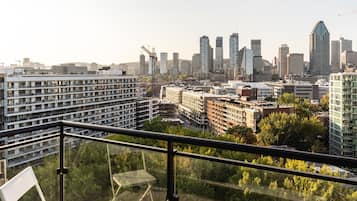 A cityscape with modern high-rise buildings, a construction crane, and a balcony with a chair.