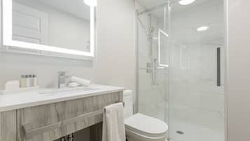 A modern bathroom with a glass shower enclosure, a marble vanity, and a large mirror.