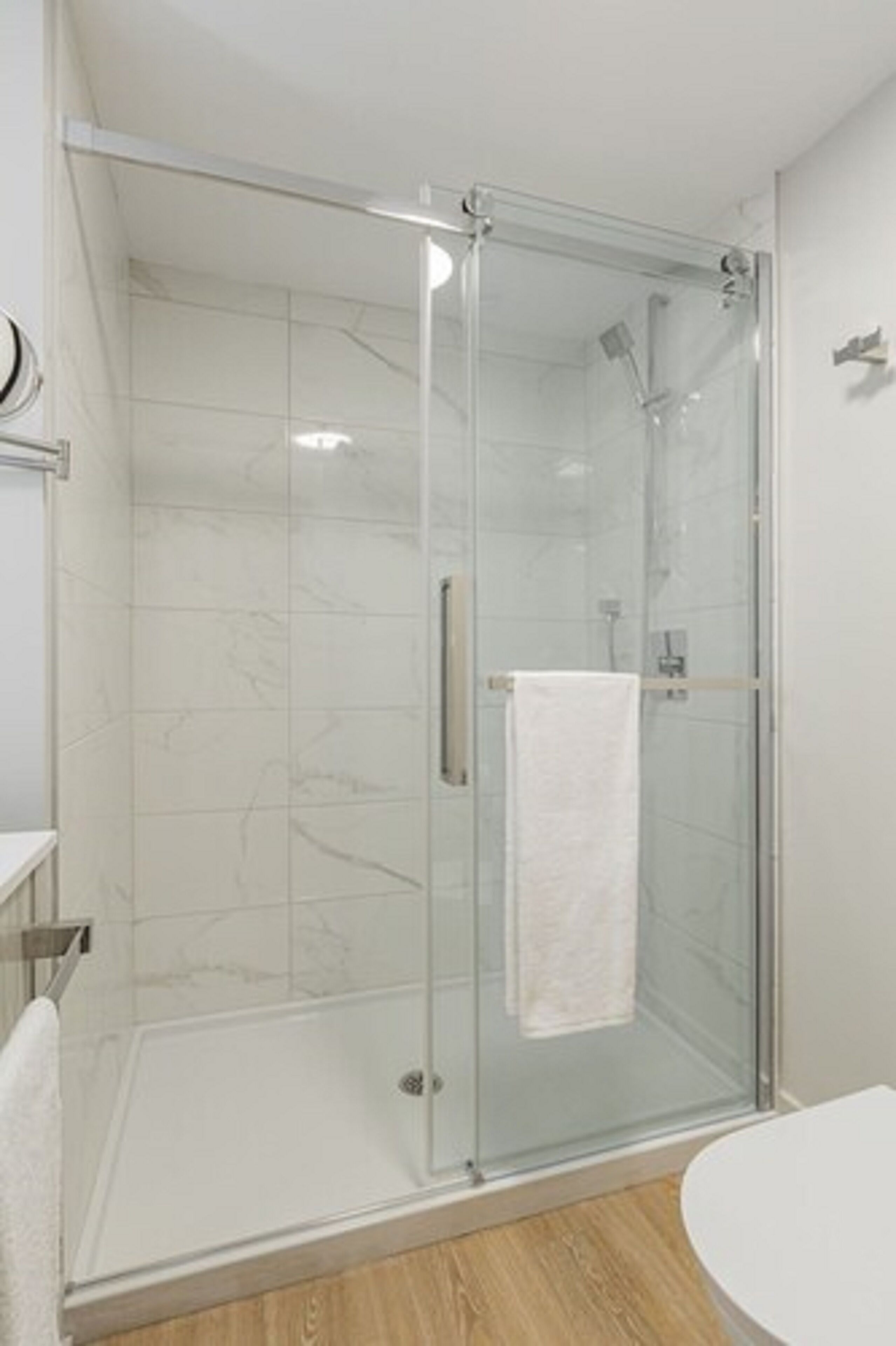 A glass-enclosed shower with a white towel hanging on the door handle.