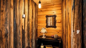 A rustic wooden room with a mirror, a table with a lamp, and a chair. - Sítio Morada do Pai com Sinuca e Piscina - Canelinha - SC (Canelinha)