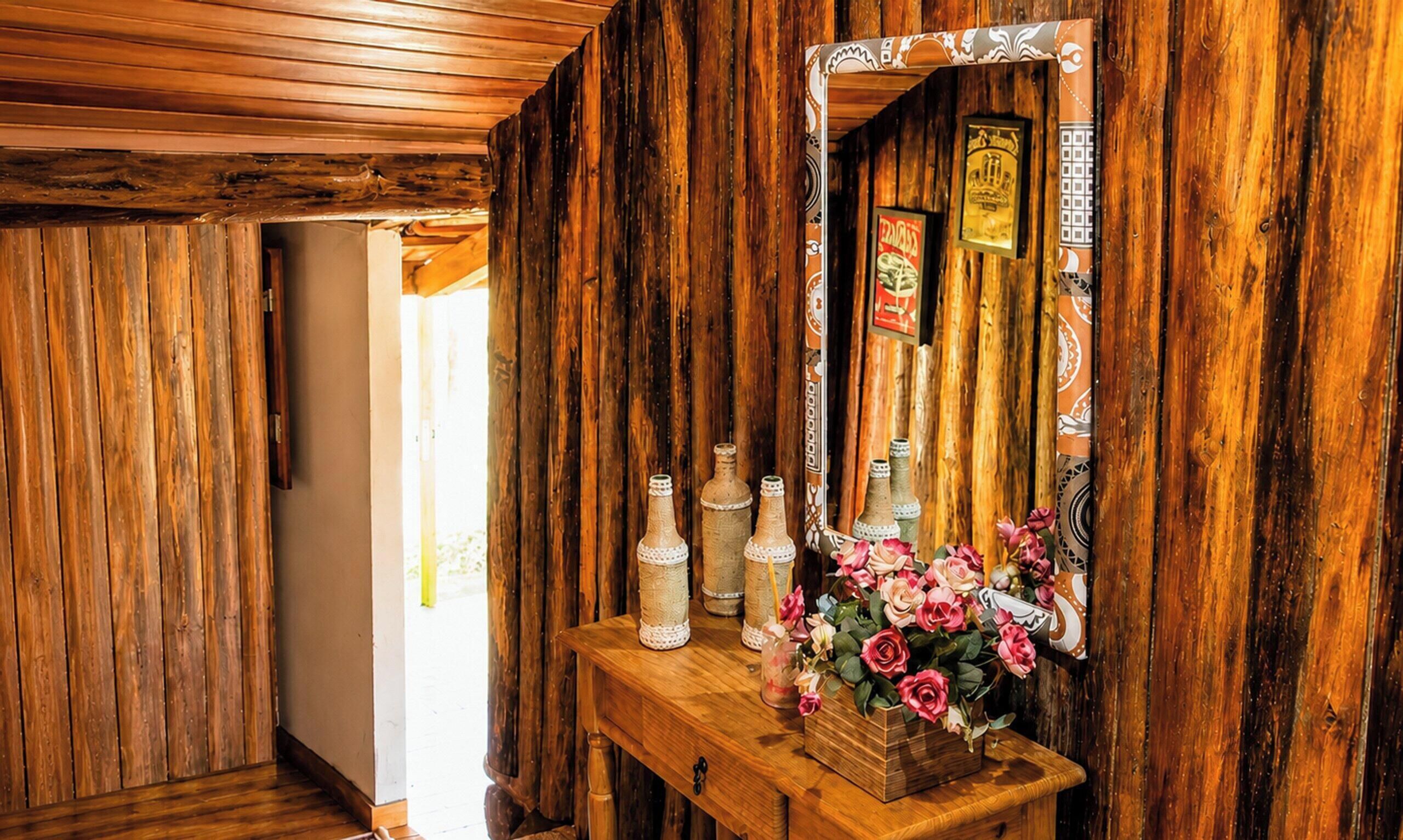 Un intérieur en bois avec un banc en bois, un miroir et des bouteilles décoratives.
