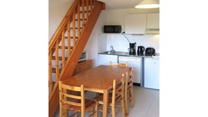 A kitchen with a wooden table and chairs, a microwave, a coffee maker, and a dishwasher. - Cosy apartment for 6 guests with TV, terrace and pets allowed (Carcans-plage)