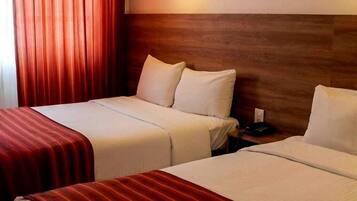 A hotel room with two beds, a wooden headboard, a red-striped bedspread, and a wall-mounted light fixture.