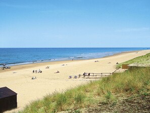 A beach with people sunbathing and walking along the shore.