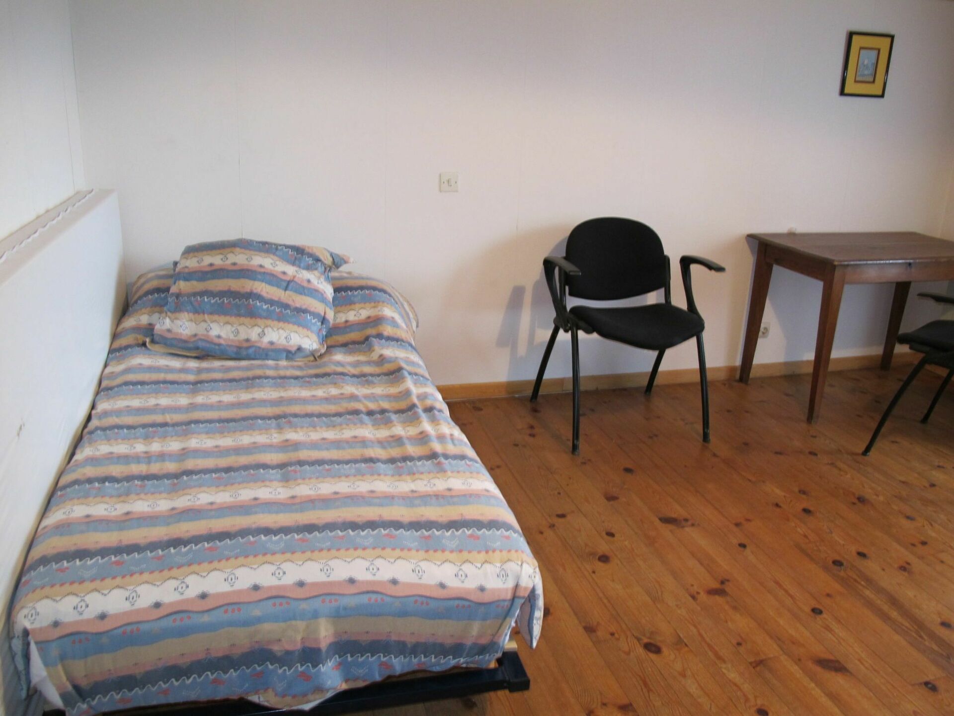 A small room with a bed, a chair, and a table.