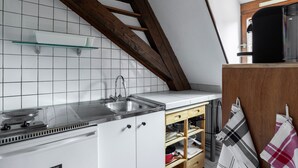 Une cuisine avec des armoires blanches, un évier en acier inoxydable et une étagère en verre.