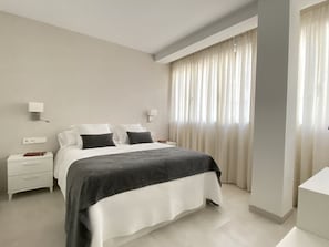 A modern hotel room with a large bed, bedside tables, and a window with curtains. - HNN Granada (Granada)