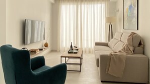 Una sala de estar moderna con un sofá, una mesa de centro, un televisor y una lámpara de pie.
