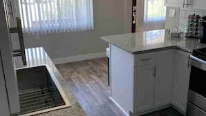 A modern kitchen with white cabinets, a granite countertop, and a stainless steel oven. -  NEAR UO, NEW RENO, SLPS 8, PET STAYS FREE, DECK/GRILL, FENCED YARD, VERY CLEAN
 (Eugene)