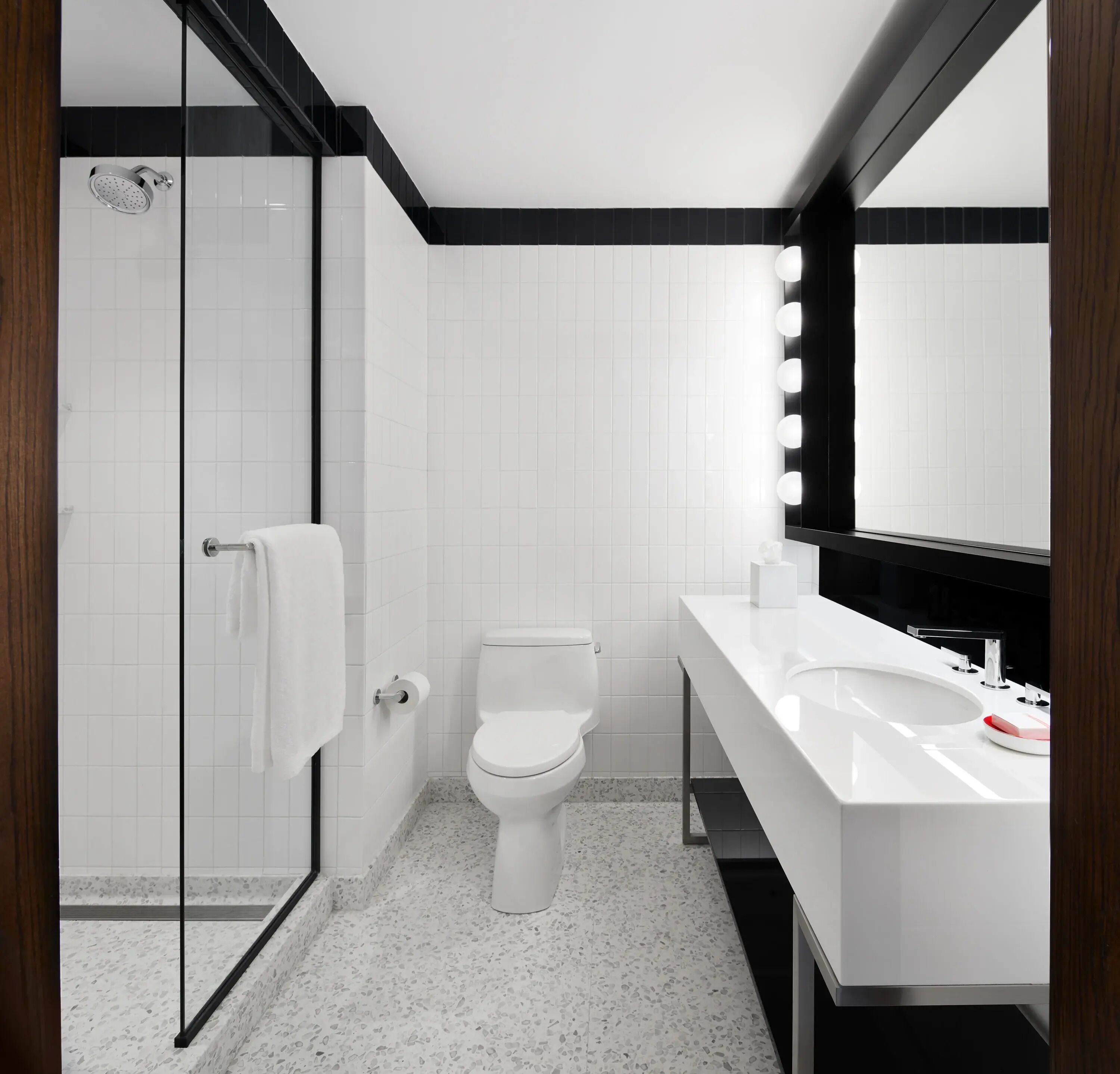 A modern bathroom with a glass shower enclosure, a white toilet, and a vanity with a mirror.