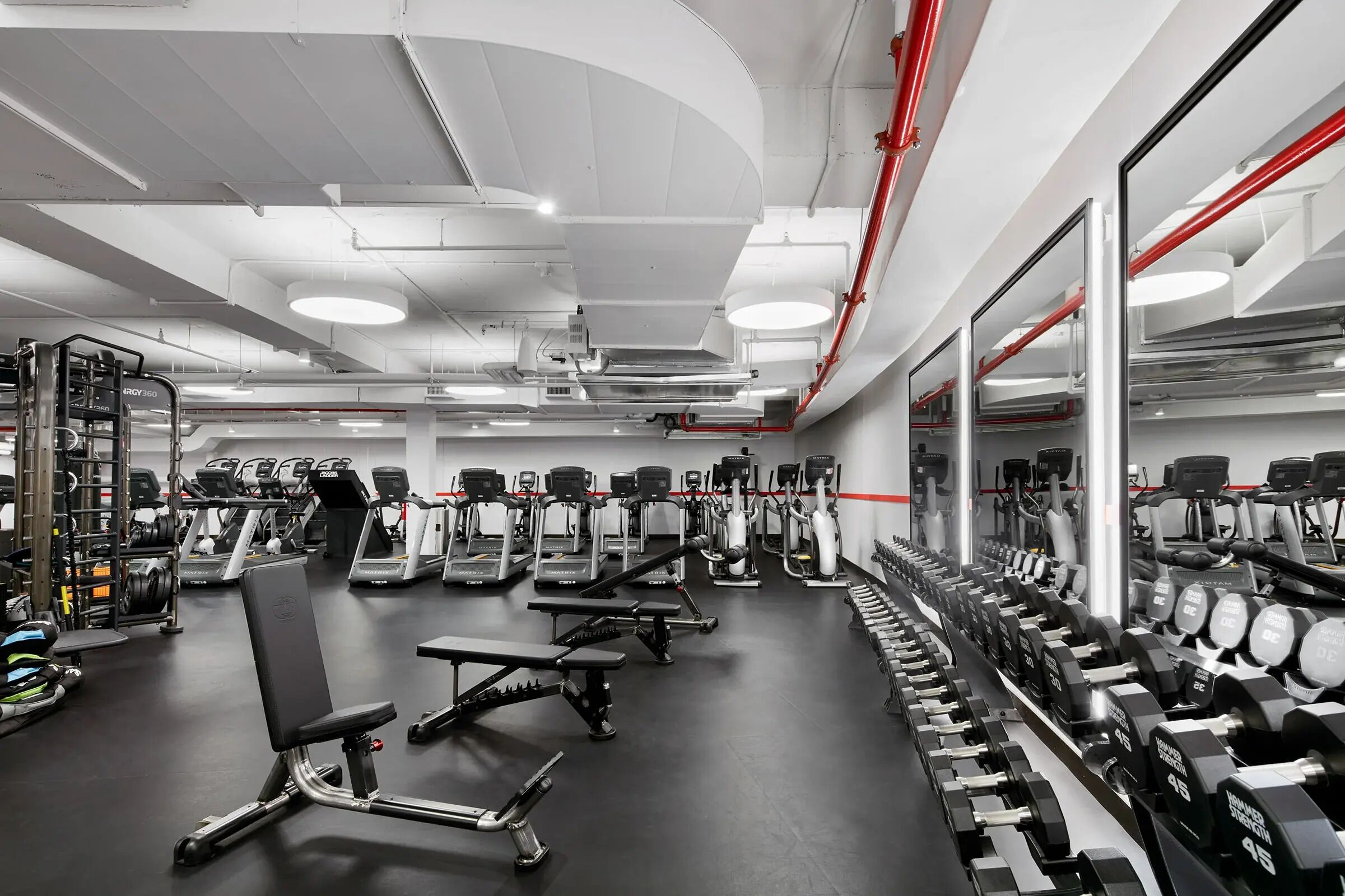 Une salle de sport équipée de tapis de course, de bancs de musculation et d’haltères.