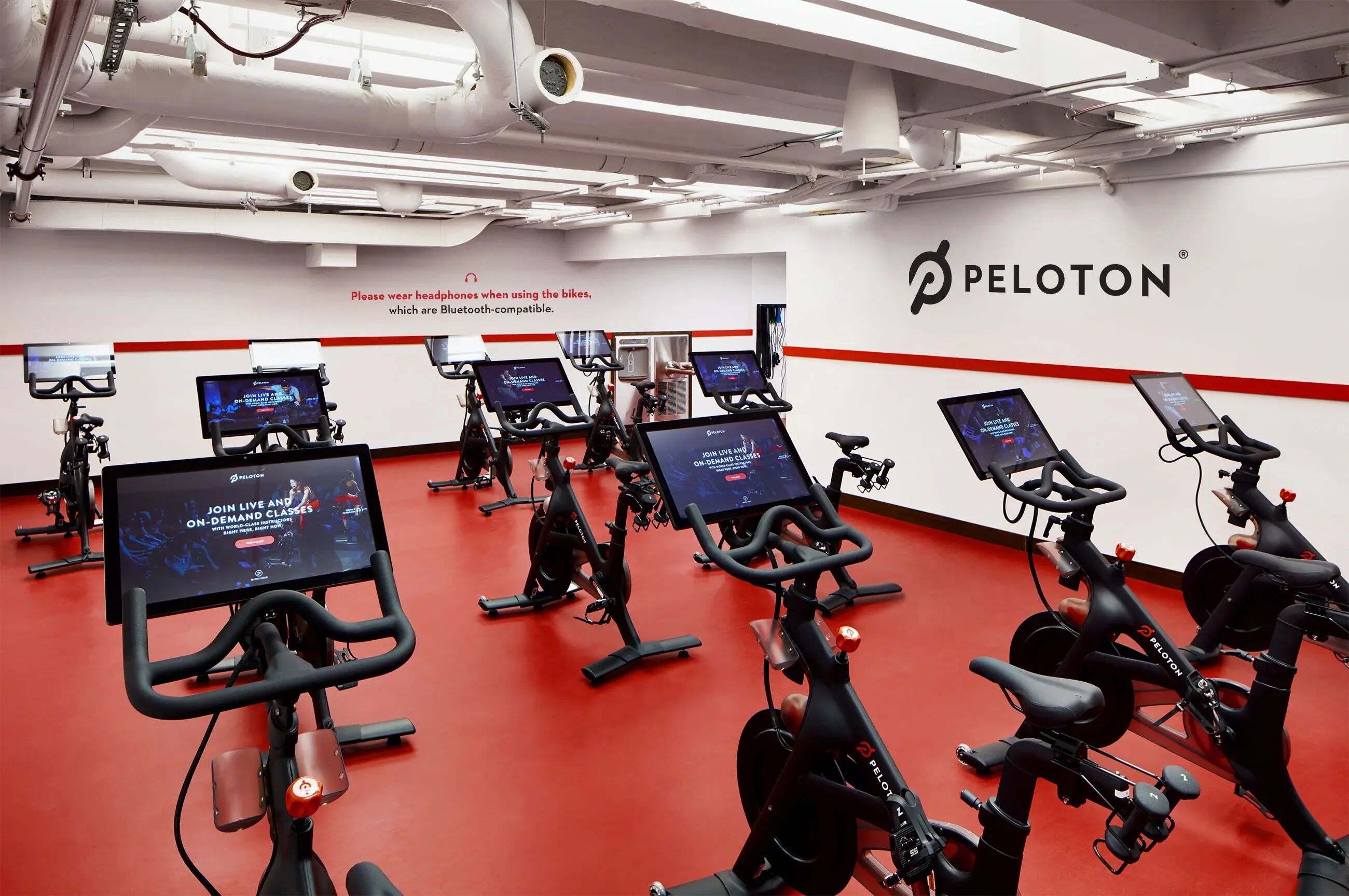 Une salle de sport équipée de vélos Peloton, avec plusieurs vélos d’exercice fixes, chacun doté d’un écran diffusant des séances d’entraînement.