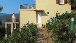 A two-story house with a balcony, a chimney, and a door. - Nice apartment for 4 people with A/C, WIFI, TV, patio, pets allowed and panoramic view (Partinello)