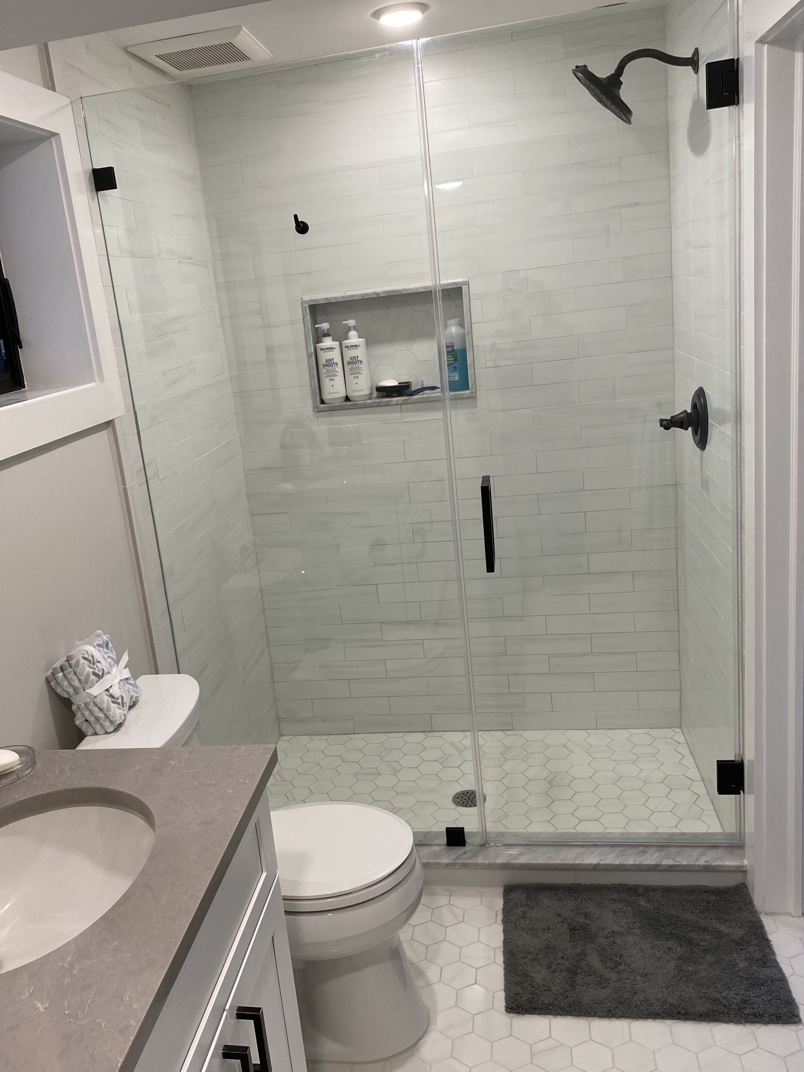 A modern bathroom with a glass-enclosed shower, a toilet, and a vanity with a sink.