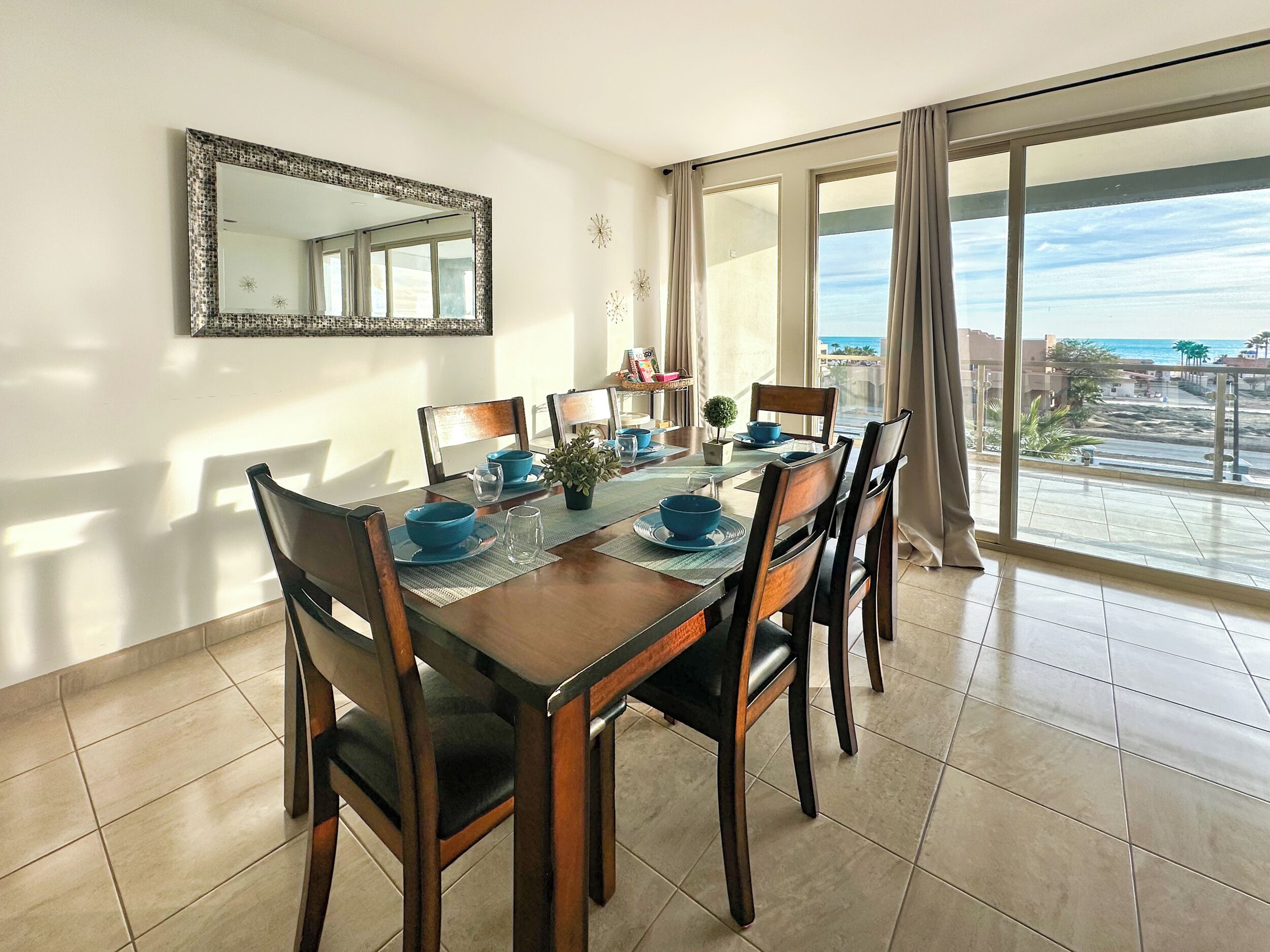 Un comedor con una mesa grande, sillas y vista al océano.