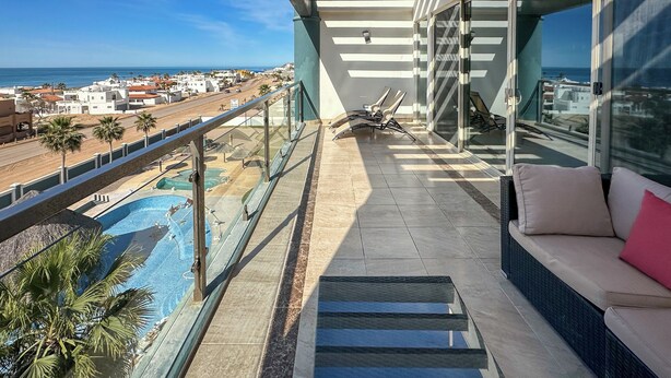 Ein Balkon mit Meerblick, ein Pool und eine Sitzecke mit Kissen.