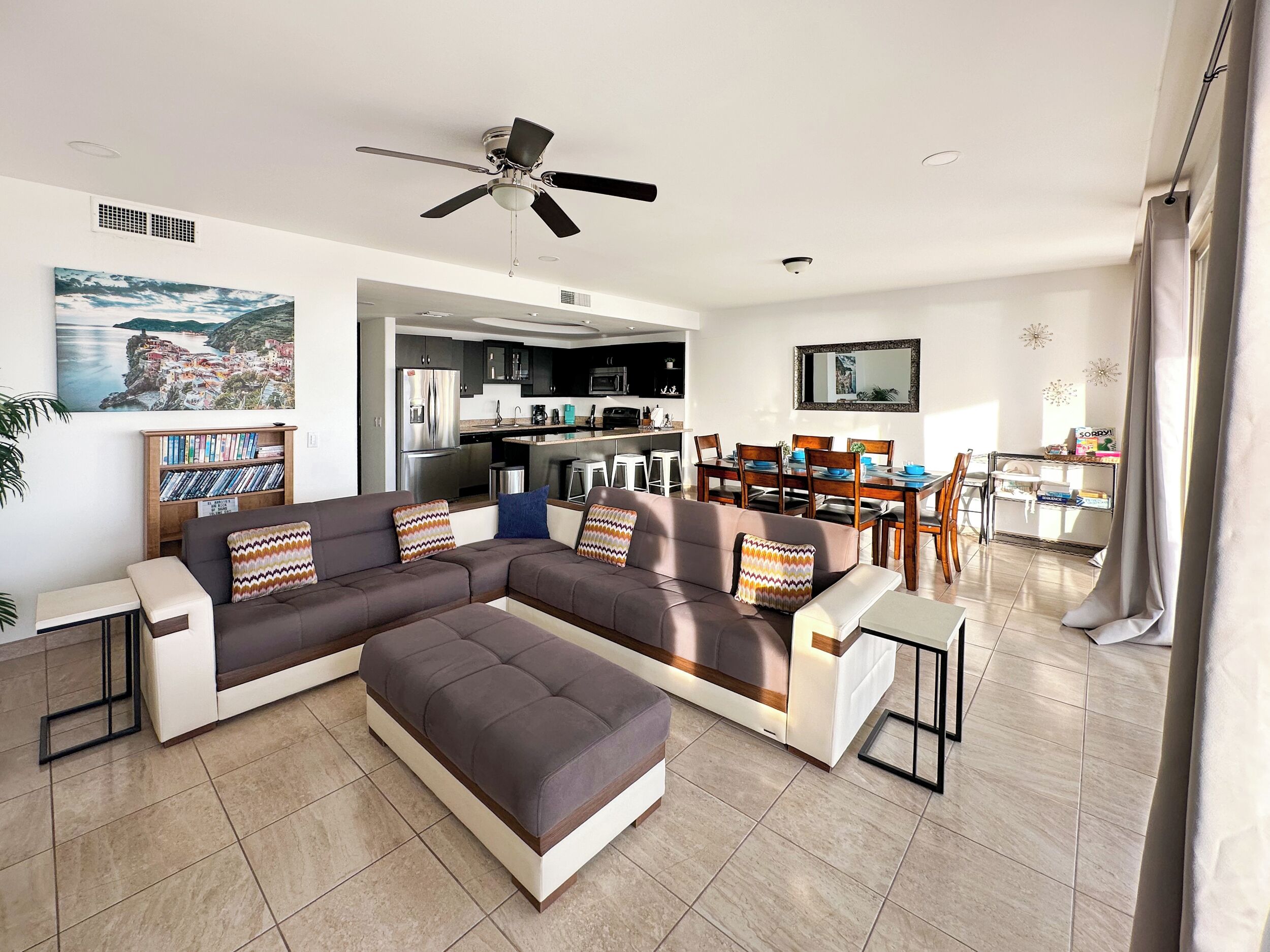 A modern living room with a sectional sofa, a dining area, and a kitchen in the background.