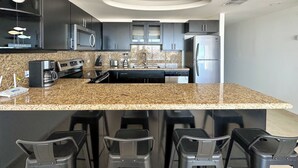 Eine moderne Küche mit Granit-Arbeitsplatten, Edelstahlgeräten und einer zentralen Kochinsel mit Barhocker.