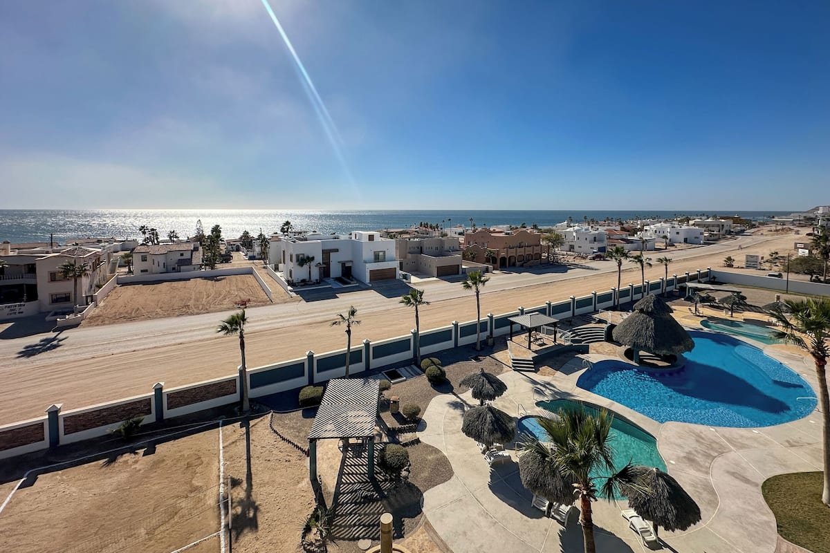 Un resort con piscina, palmeras y vistas a la playa.