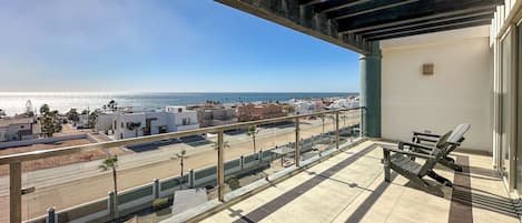 A balcony with a view of the sea and buildings.
