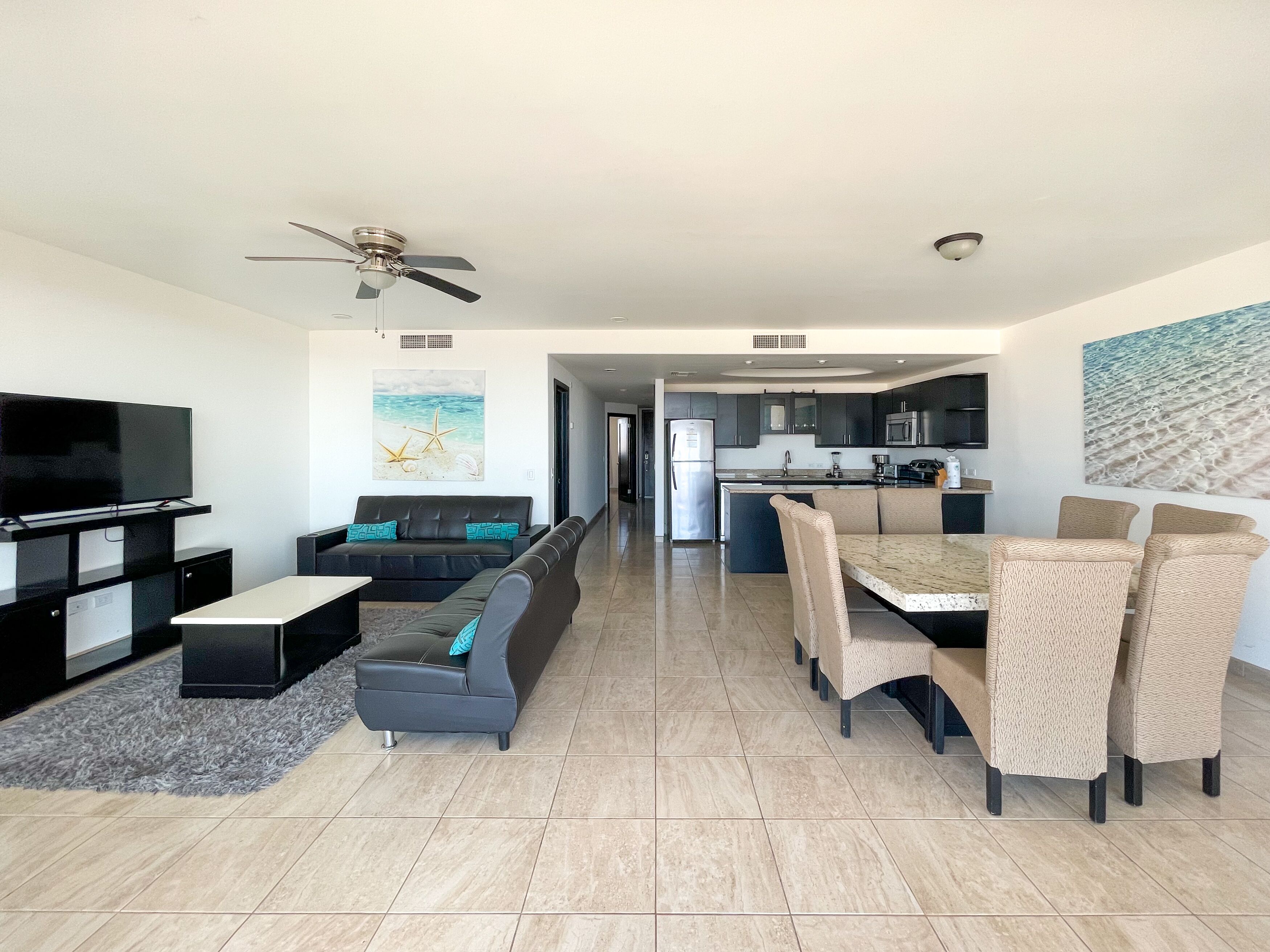 A modern living room with a flat-screen TV, sofa, and dining area with chairs.