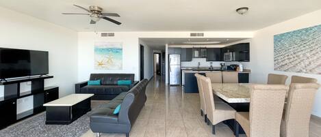 A modern living room with a flat-screen TV, sofa, and dining area with chairs.