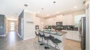 A modern kitchen with white cabinets, a central island with bar stools, stainless steel appliances, and pendant lighting. - (AG2770) Storey Lake VILLA 5/5, Private Pool & Free Waterpark (Kissimmee)