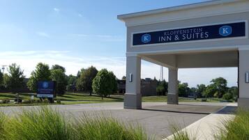 The entrance to Klopfenstein Inn & Suites with a clear sky and greenery in the background.