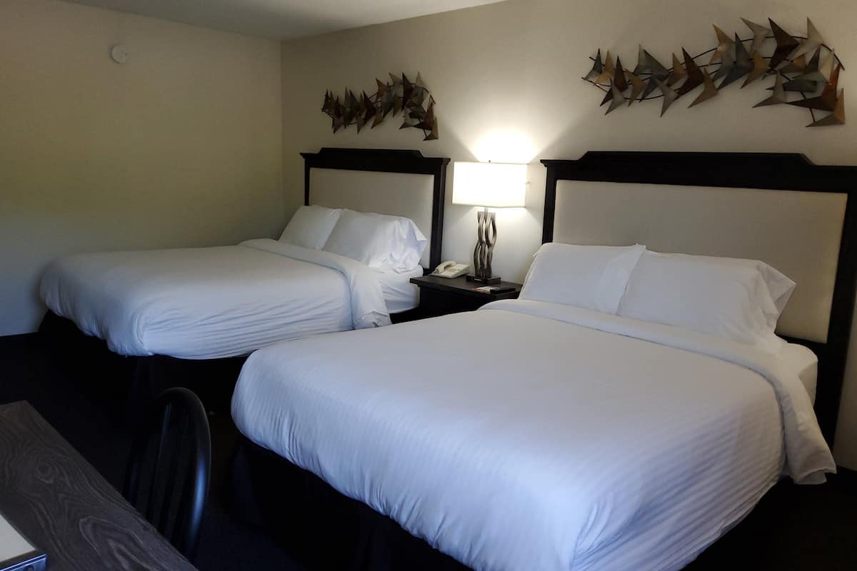 Une chambre d’hôtel avec deux lits, un bureau et une lampe.