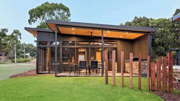 A modern house with a covered patio, large windows, and a stone fireplace.