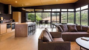 A modern kitchen with a central island, dining area with chairs, and a sofa. - Artisan Gunyulgup—Luxe Lakeside Wellness Hideaway (Yallingup)