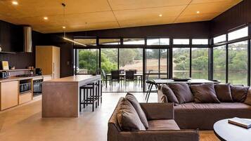 A modern kitchen with a central island, dining area with chairs, and a sofa.