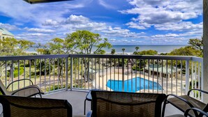 Ein Balkon mit Blick auf einen Swimmingpool und den Ozean.