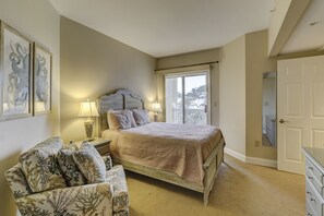 Un dormitorio con cama, una silla, cómoda y una puerta.