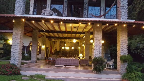 A covered outdoor area with stone pillars, a checkered floor, and a seating arrangement. - Private rainforest villa nestled in the cool mountains of El Valle de Antón.. (Anton Valley)