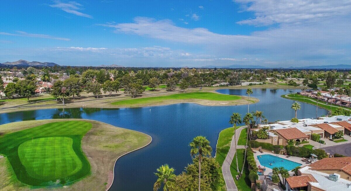 Ein Golfplatz mit See, Schwimmbad und Wohnhäusern.